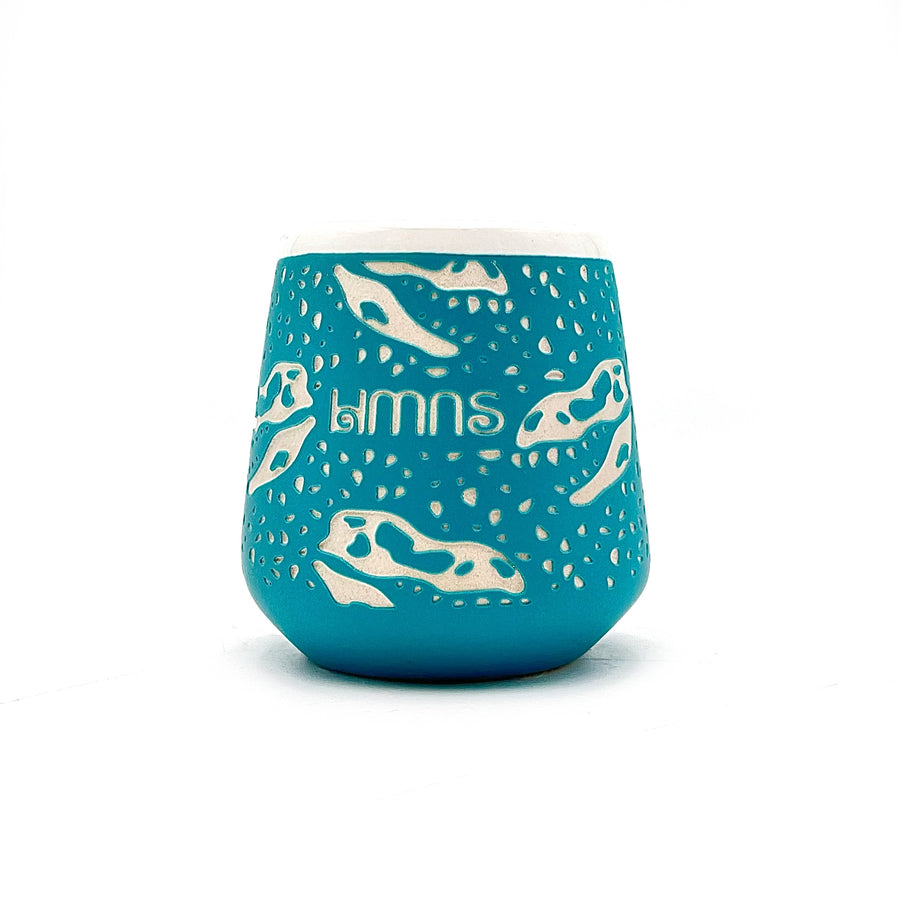 Blue ceramic shot glass with white dinosaur illustrations on a white background