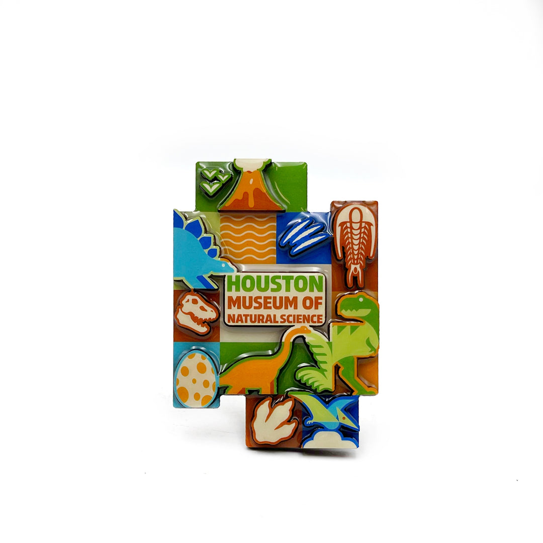 a bright and colorful magnet with blocky shape featuring the museum name, some dinosaurs, fossils, and a volcano