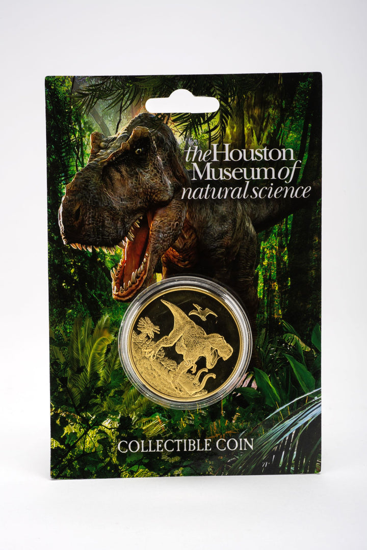 Packaged collectible coin with a dinosaur motif, from the Houston Museum of Natural Science, displayed on a card with a dinosaur image.