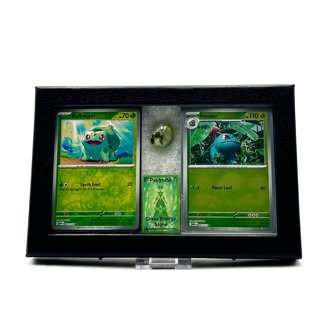 Two Pokemon trading cards featuring Bulbasaur and Ivysaur in a display case with a tumbled prehnite stone against a white background