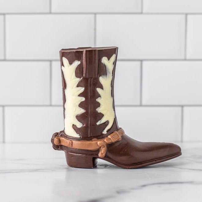 Chocolate cowboy boot with white chocolate star patterns on a white tiled background
