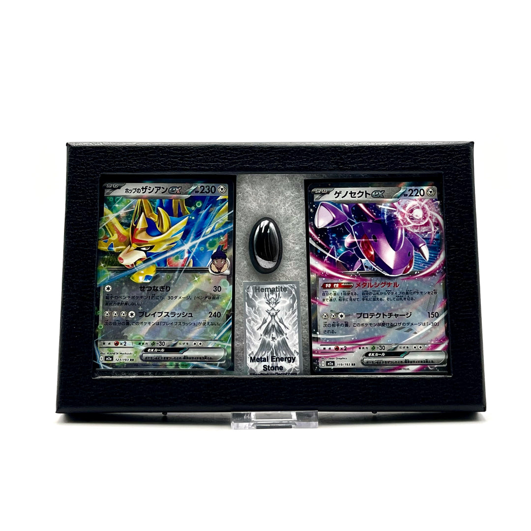 Two Japanese pokemon cards featuring Zacian and Genesect  along with a polished hematite stone, all in a black frame against a white background 