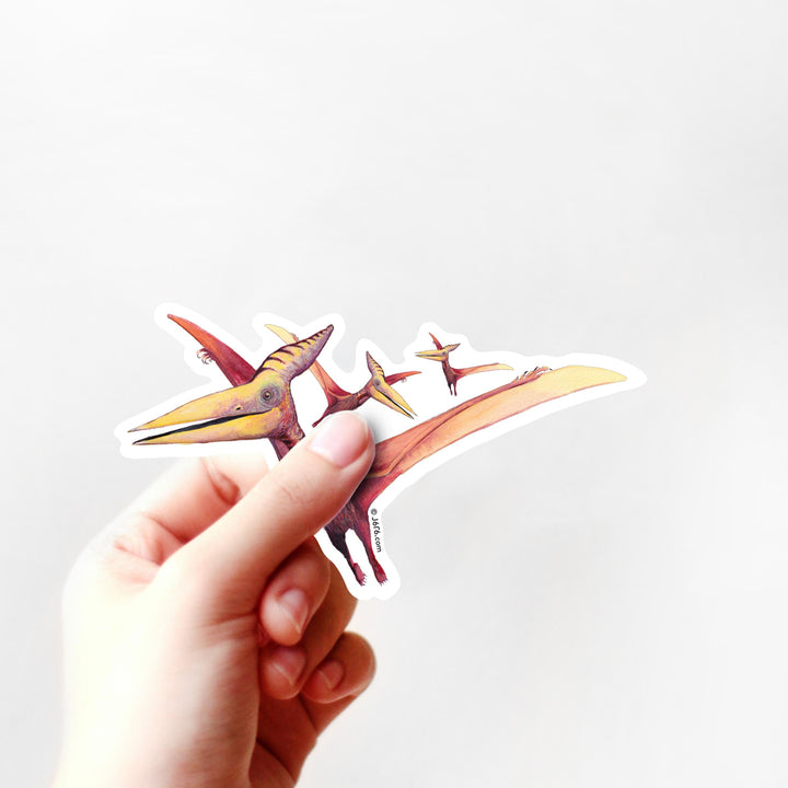 Hand holding a dinosaur-shaped sticker against a white background