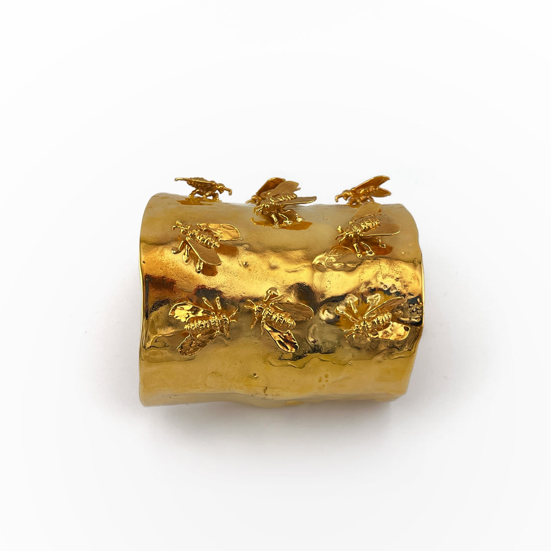 gold-tone brass cuff with nine 3D bees on it