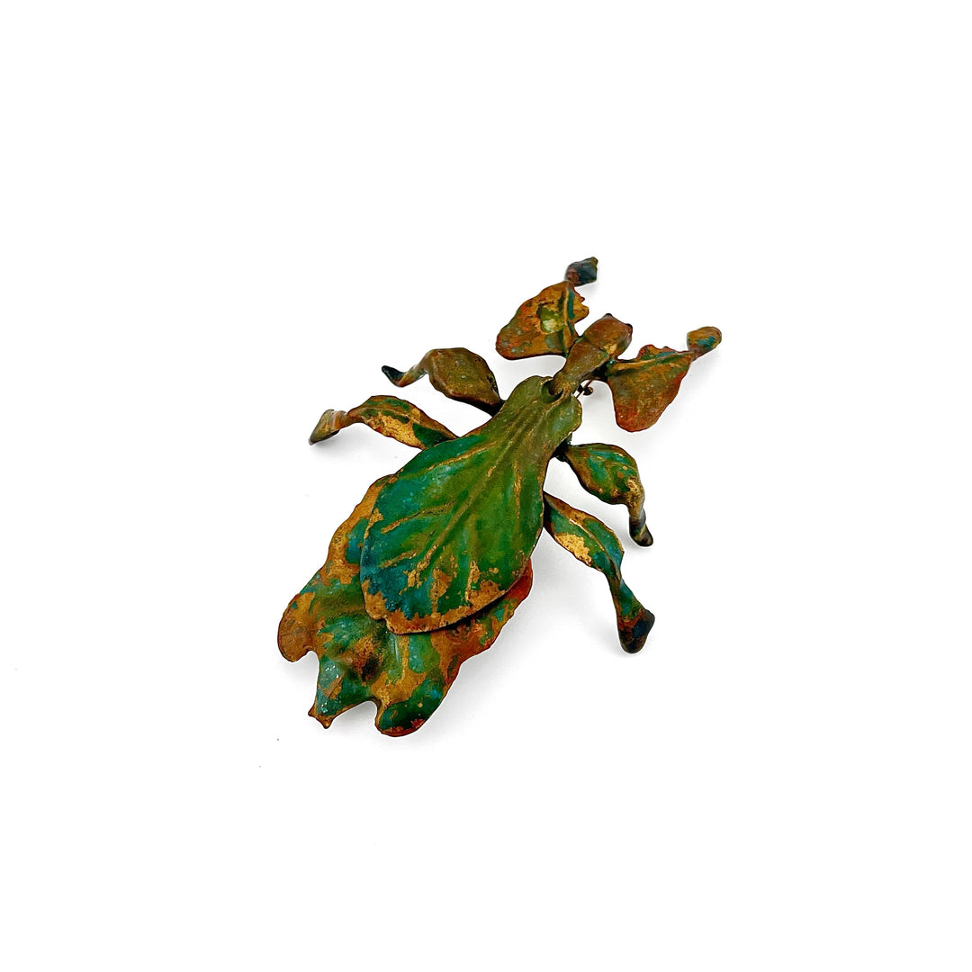 Brass and green patina leaf insect brooch on a white background
