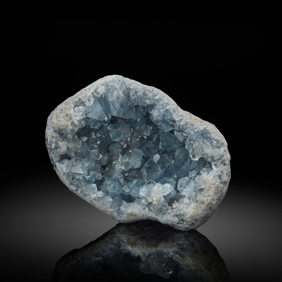 a celestite geode with light blue crystals inside, set against a black background