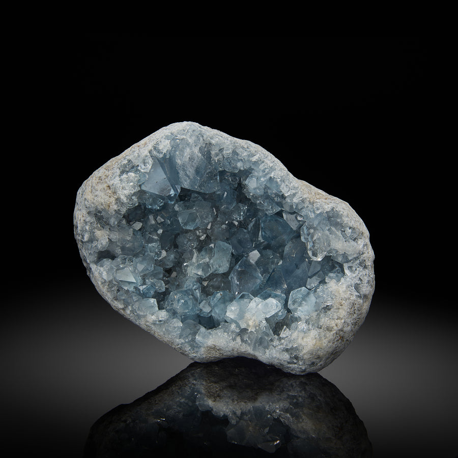 a celestite geode with light blue crystals inside, set against a black background