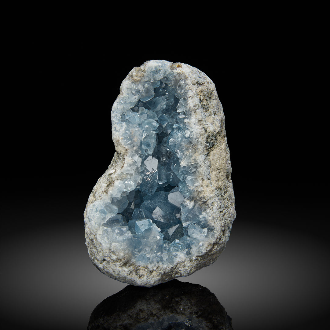 a celestite geode with light blue crystals inside, set against a black background