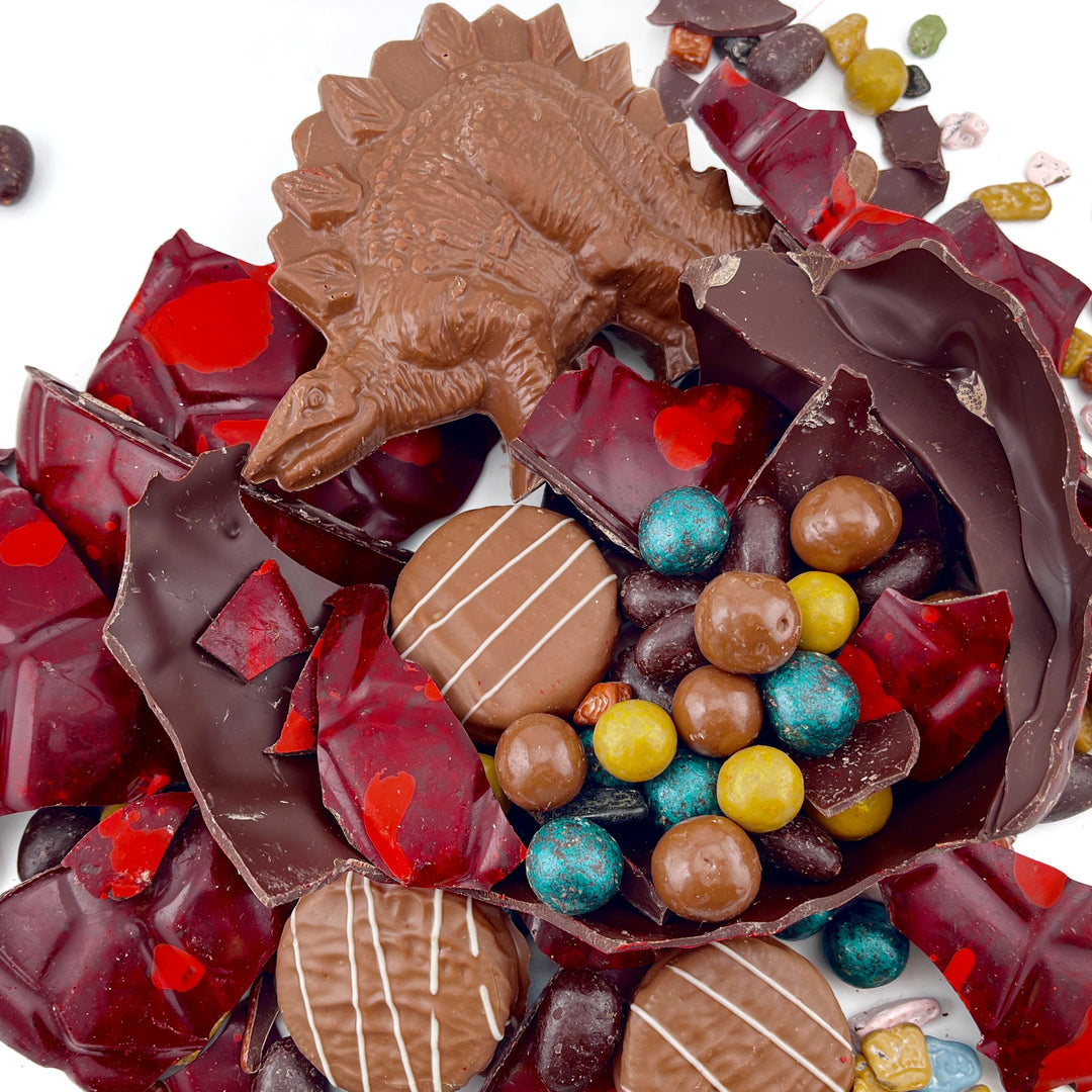 Assorted chocolates including a chocolate dinosaur figure on a white background