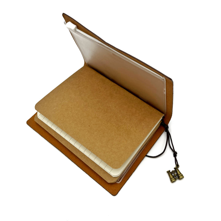 interior shot of journal showing a sliding zipper clear bag in the journal, as well as a lined paper insert