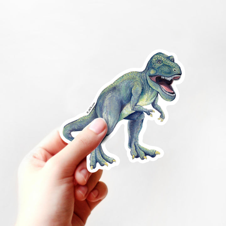 Hand holding a dinosaur sticker against a white background