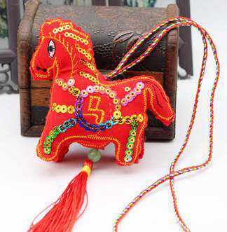 Decorative horse ornament with sequins and tassels on a white background