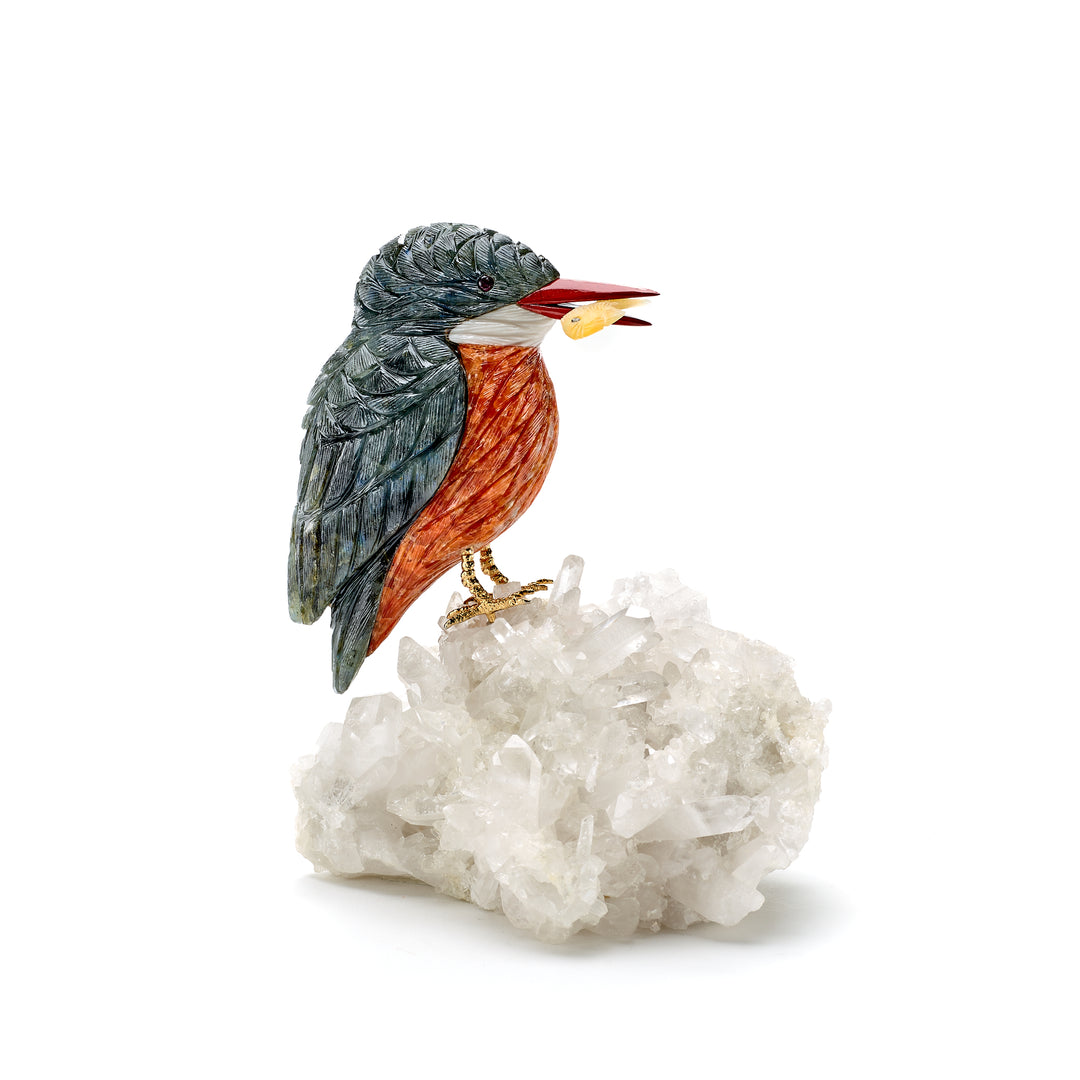 A sculpture of a kingfisher perched on a fluorite fish on a quartz carving, with orange and white calcite colors and a jasper beak.