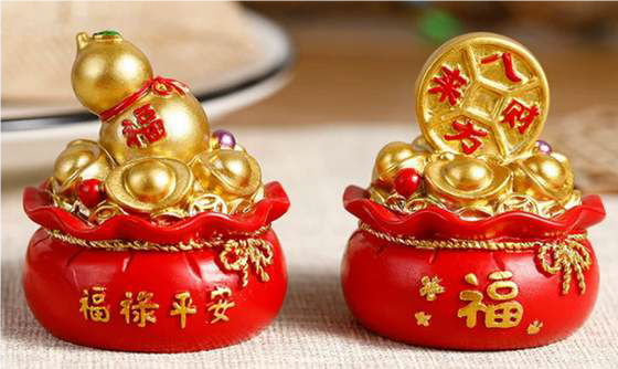 Two decorative items with gold figures and red bases on a wooden surface.