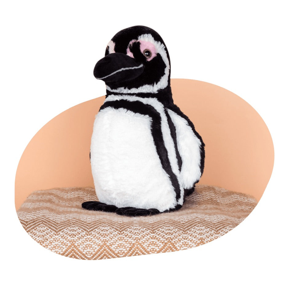 black and white penguin plush on an orange and white patterned cushion