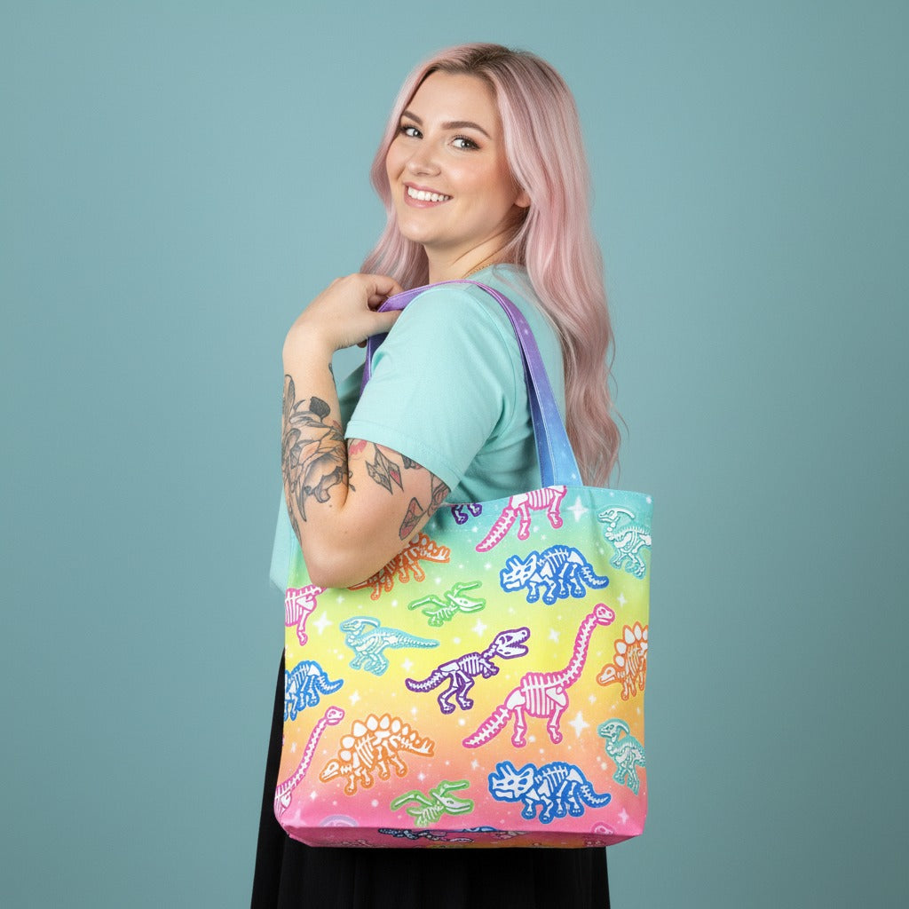 Woman holding a colorful tote bag with dinosaur design against a solid background