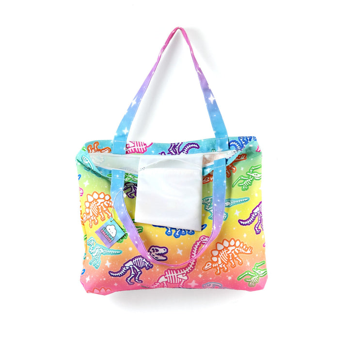 Colorful tote bag with dinosaur design with interior pocket on display, against a white background