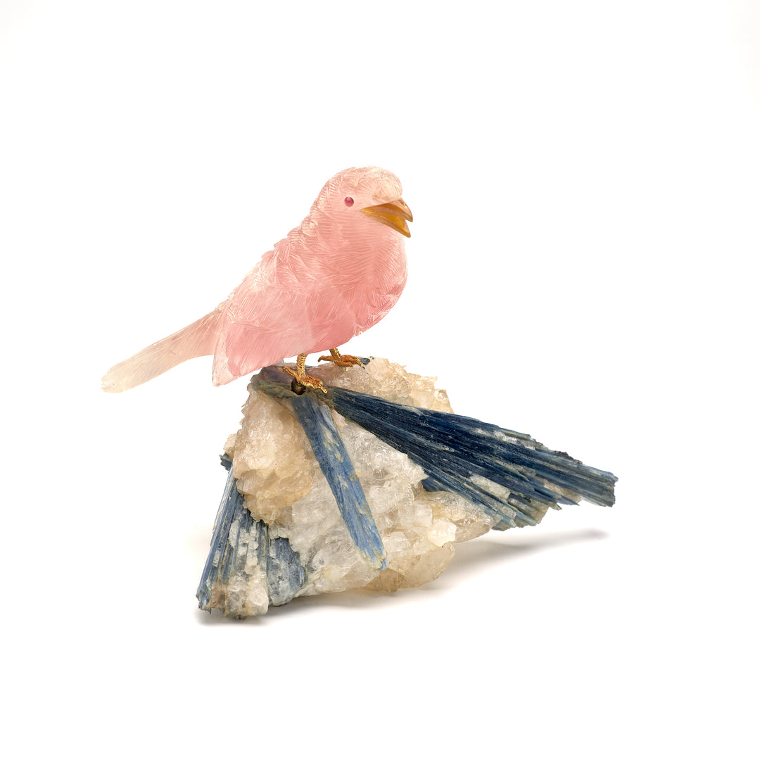 A rose quartz wren carving with garnet eyes and agate beak, mounted on a kyanite and quartz base.