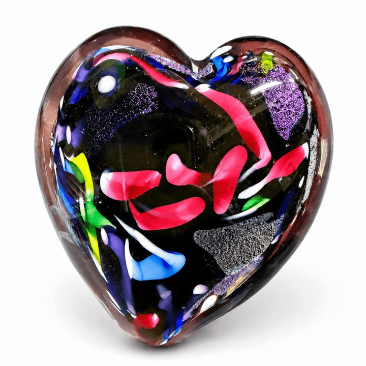 A heart-shaped glass art piece featuring a black base with vibrant, multicolored swirls of pink, purple, blue, green, and red, set against a plain white background.