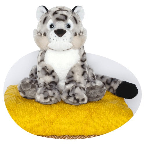 a white and black spotted snow leopard plush toy sits on a yellow textured cushion