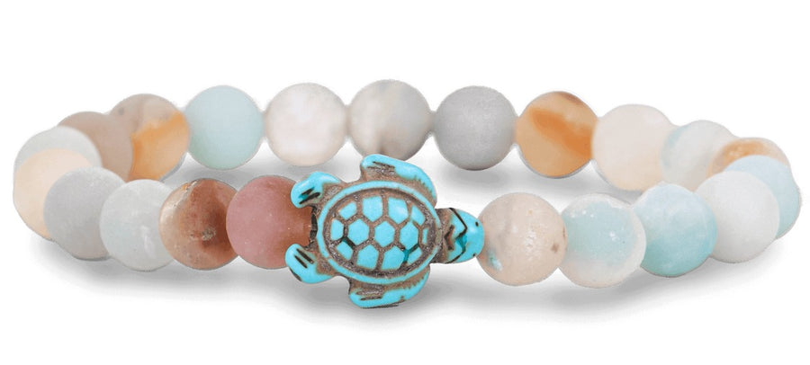 a bracelet with sky-tone beads and a dyed howlite turtle-shaped bead on white background