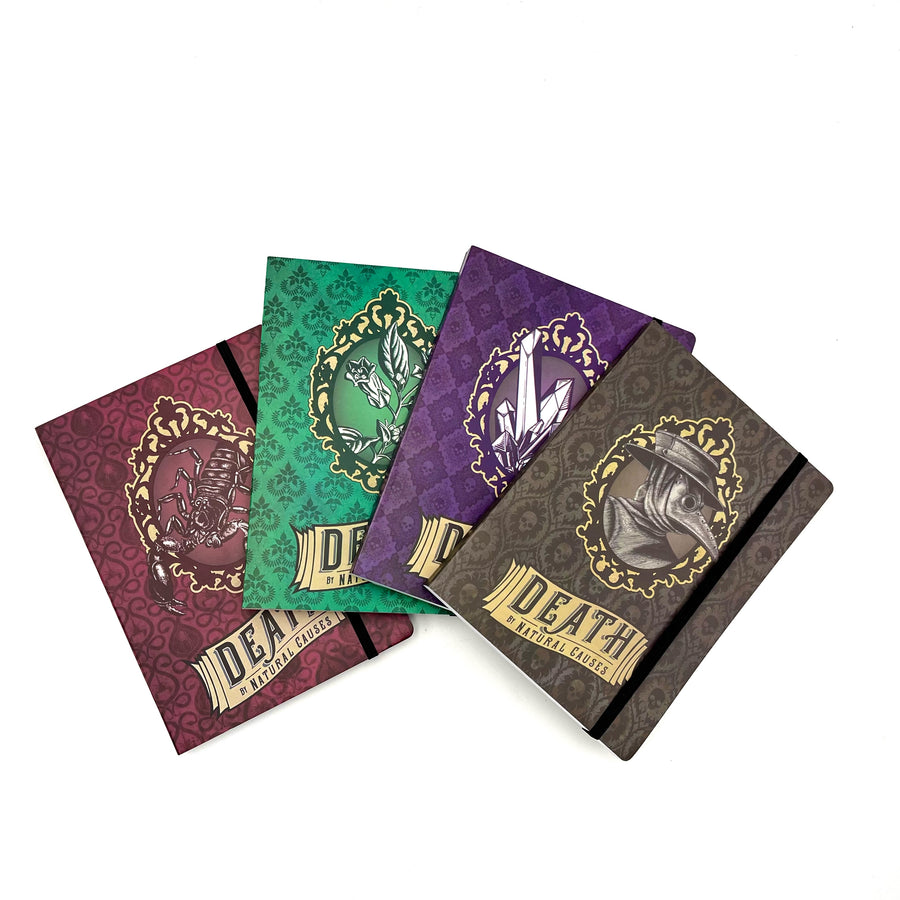 four softbound journals in red, green, purple, and black are spread across a white background