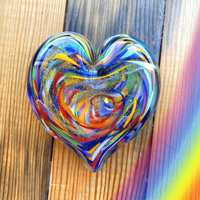 Multicolored heart-shaped glass object on a wooden surface