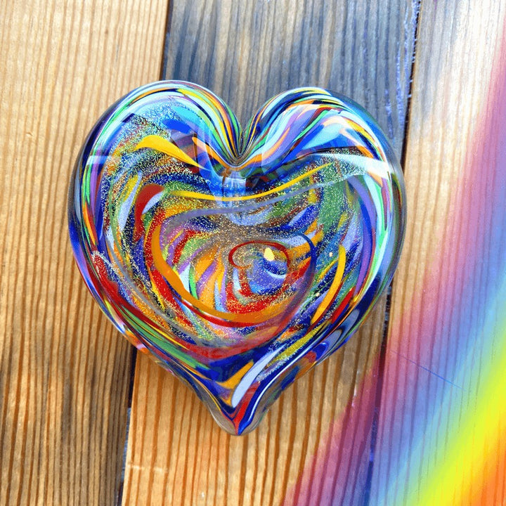 Multicolored heart-shaped glass object on a wooden surface